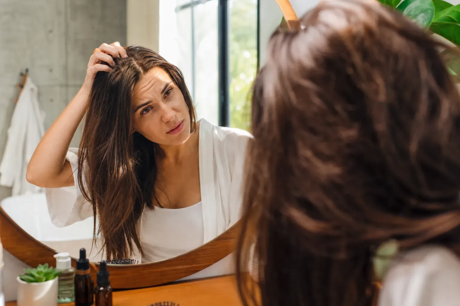 Femme examinant ses racines dans un miroir de salle de bain