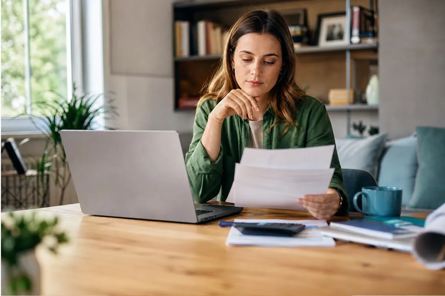 Femme consultant ses relevés bancaires devant un ordinateur portable à la maison